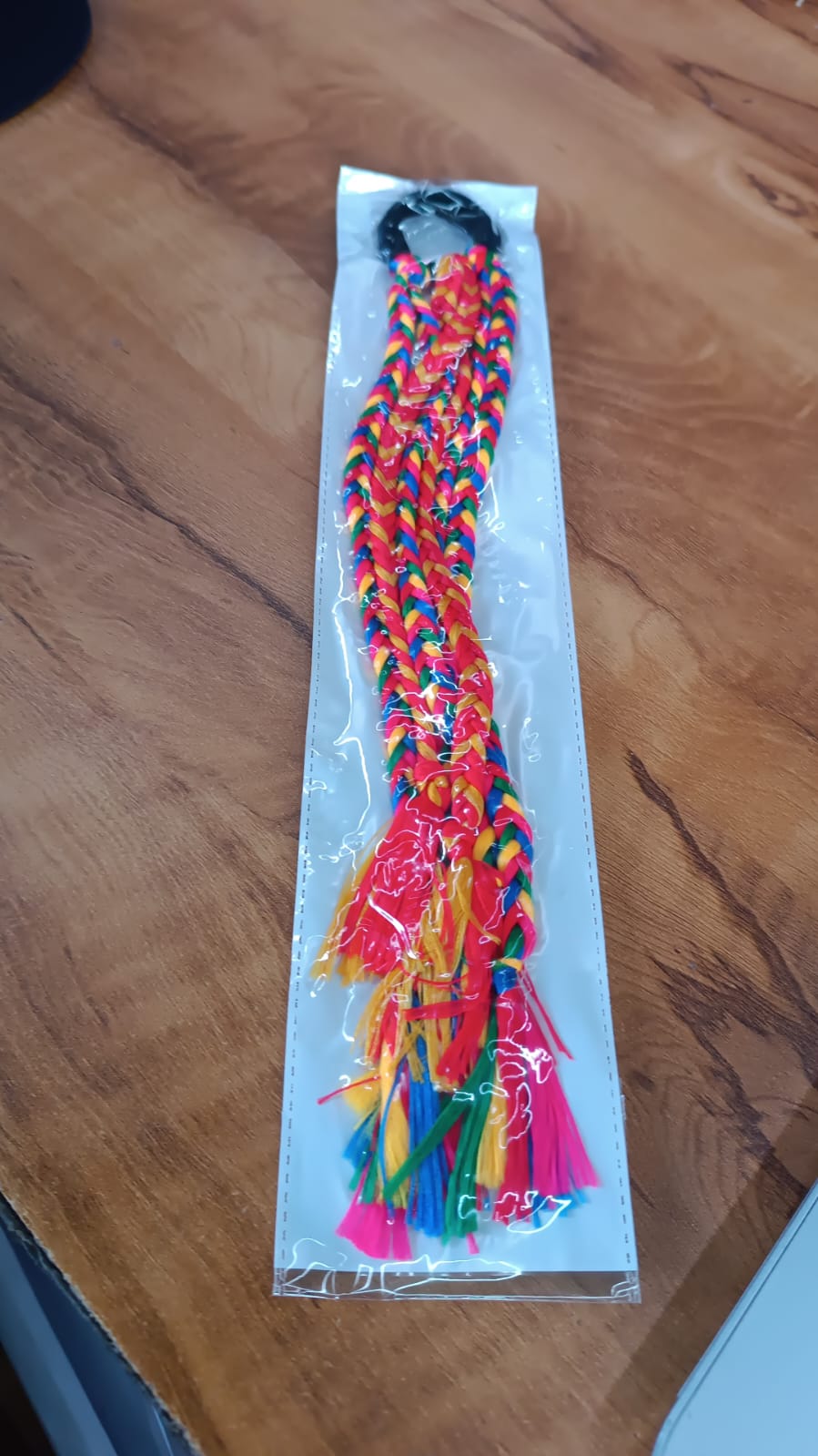 Braided hair extension hanging on display showing vibrant colors and tassels