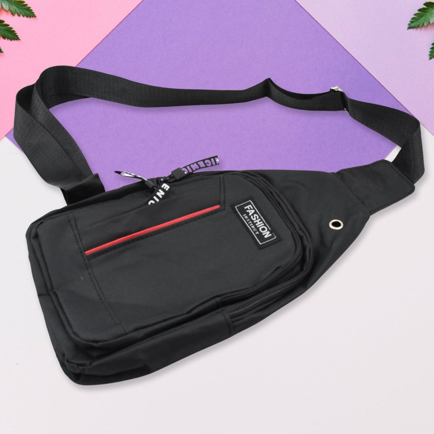 A black sling bag with a red stripe and 'FASHION' label is displayed on a purple and pink background.