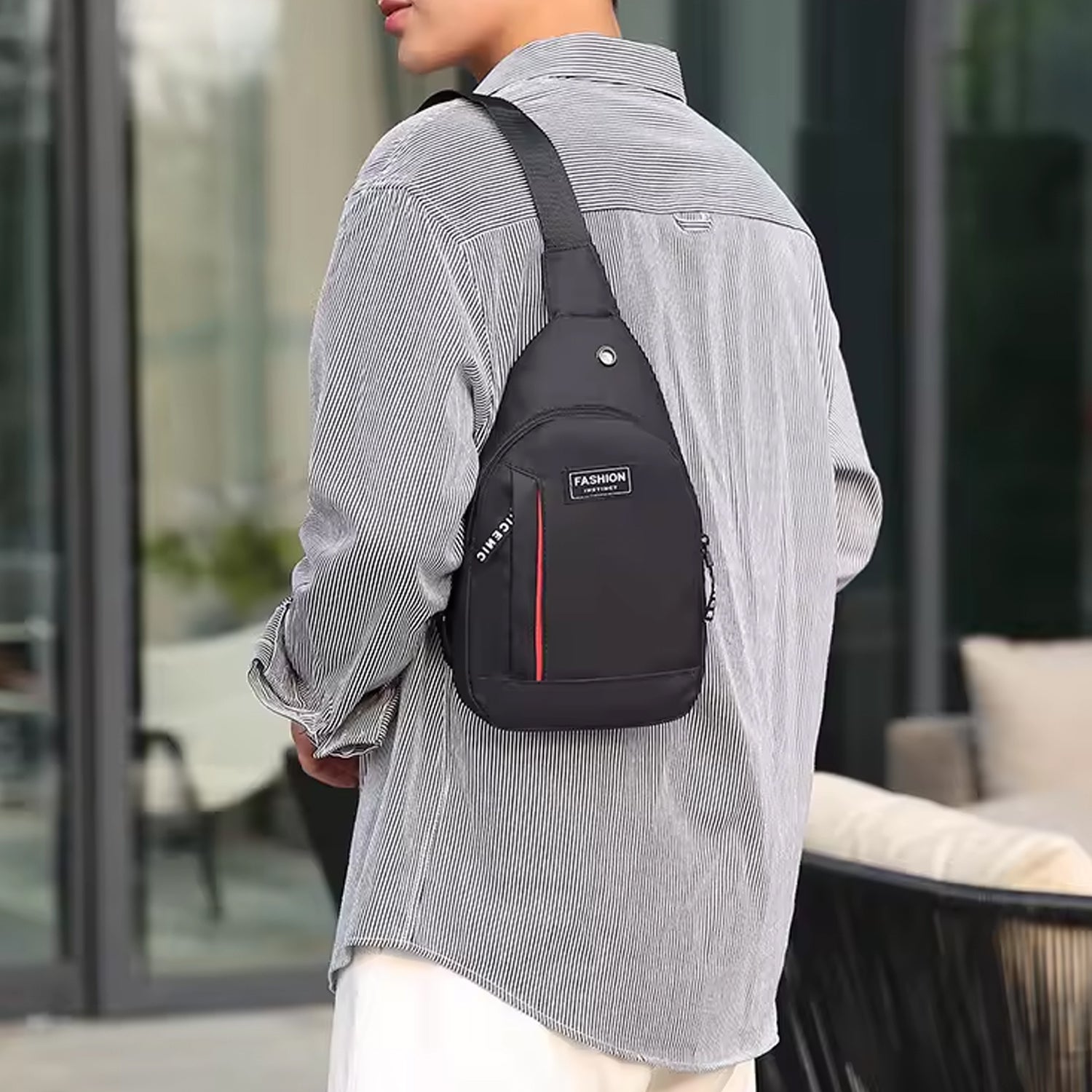 A person wears a black sling bag with red stripe and 'FASHION' label over a striped shirt, facing away.