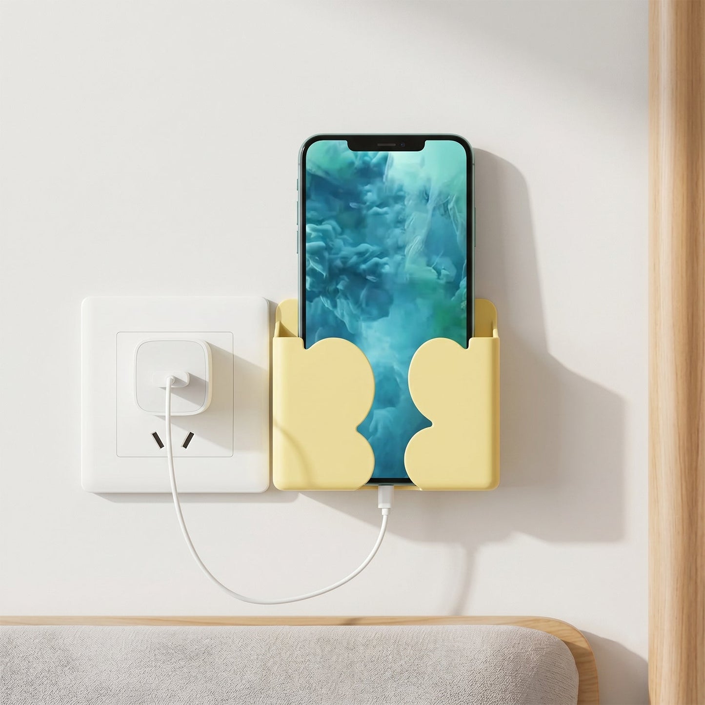 Smartphone held securely in wall mount holder next to power socket.