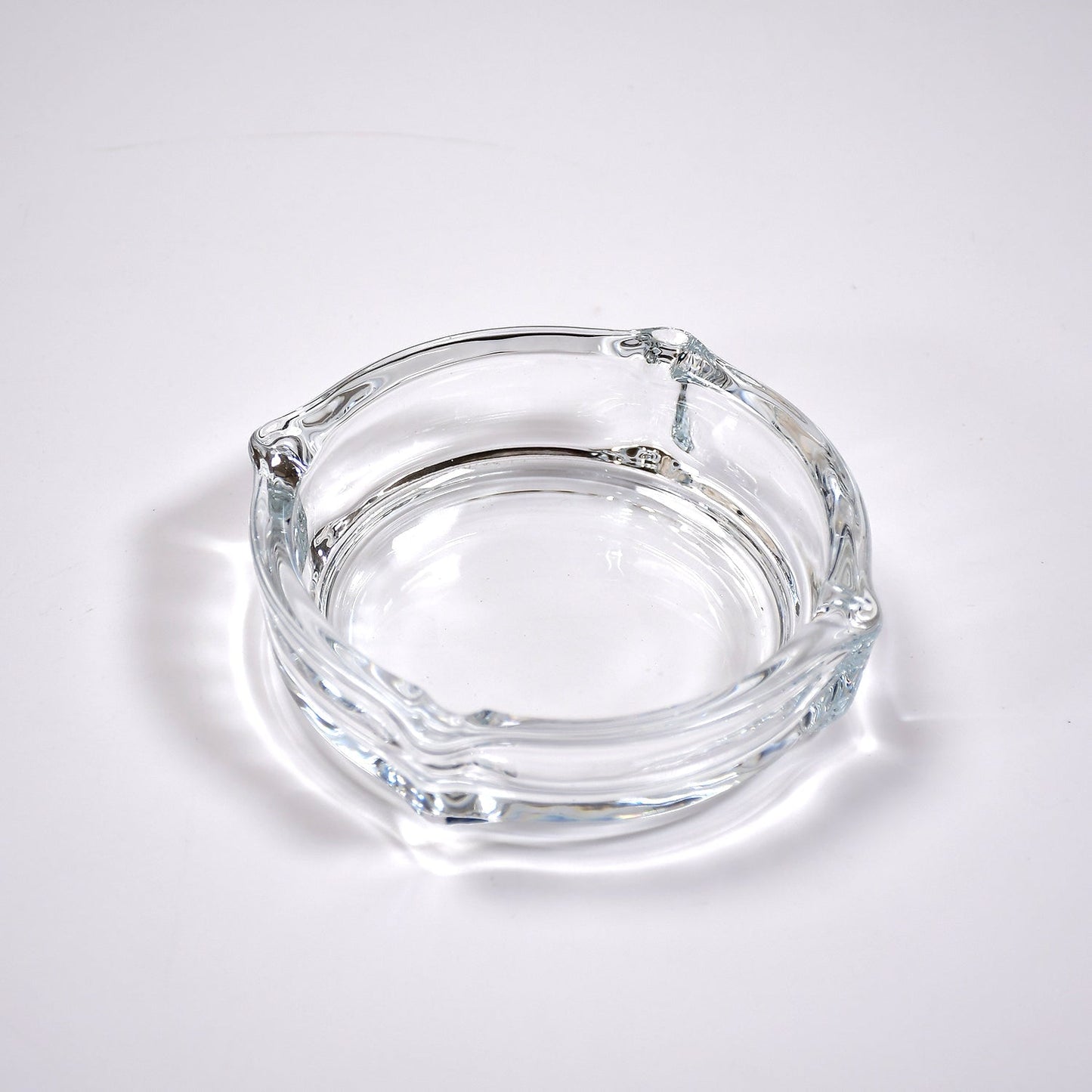 Clear glass ashtray featuring a classic round shape and convenient cigarette slots.