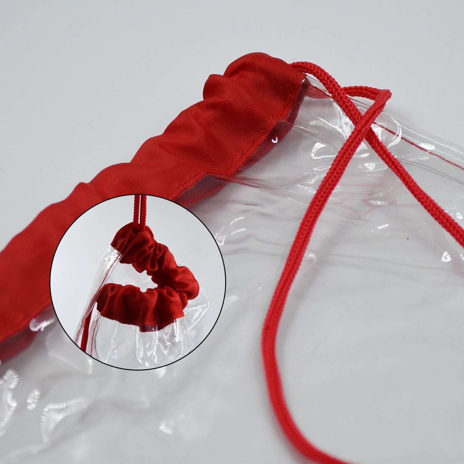 A close-up of the red drawstring and top fabric of a clear bag, with an inset circle showing a detailed view of the