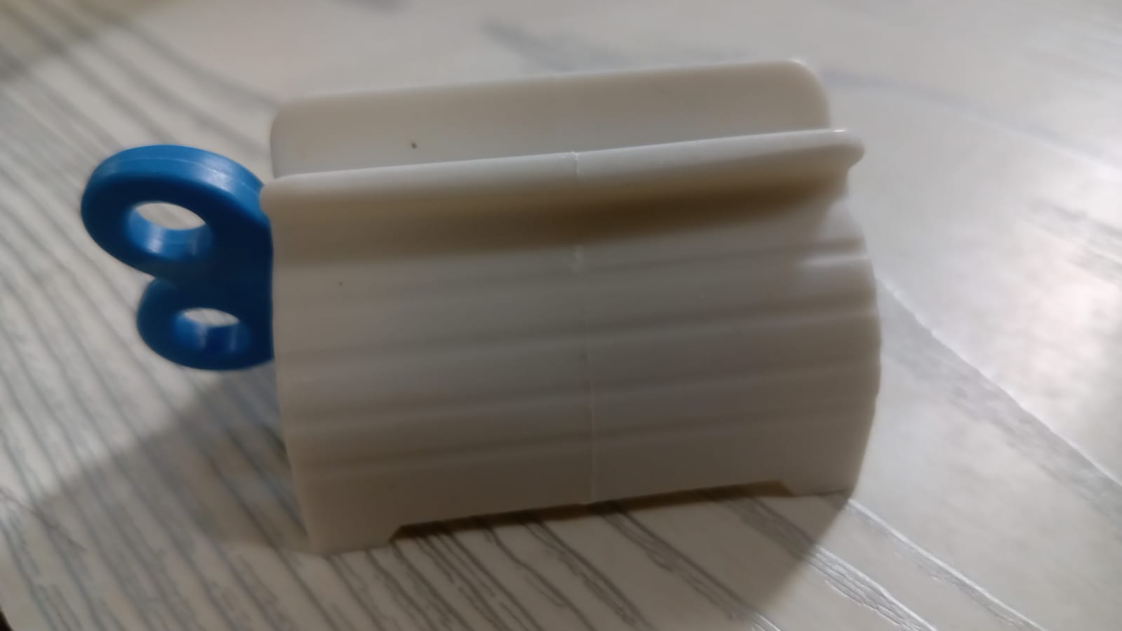 Toothpaste tube squeezer with its seat holder, emphasizing convenience and organization.